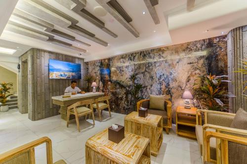 a man sitting at a table in a restaurant with a mural at Hotel Ocean Grand at Hulhumale in Hulhumale