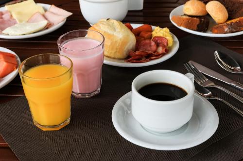 a table with plates of breakfast foods and a cup of coffee at i5 Hotel Águas Claras in Brasilia