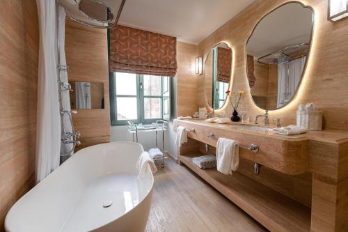 een badkamer met een bad en een grote spiegel bij Palazzo Bifora in Mdina