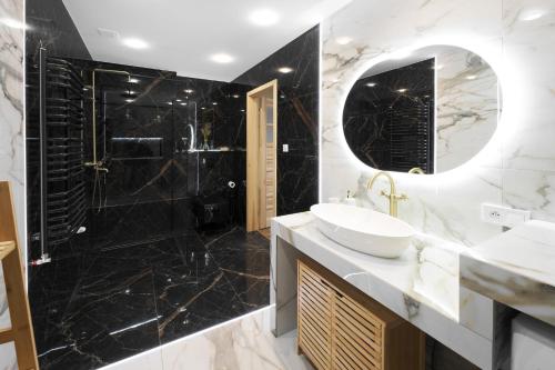 a black and white bathroom with a sink and a shower at Apartament widokowy z jacuzzi i sauną na wyłączność - Sikorówka - Dobre Miejsce in Wisła