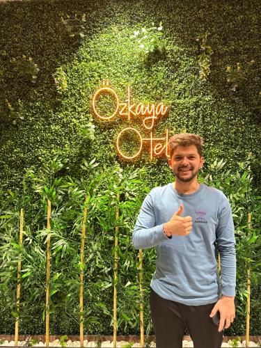 a man giving a thumbs up in front of a sign at Özkaya hotel in Sivas