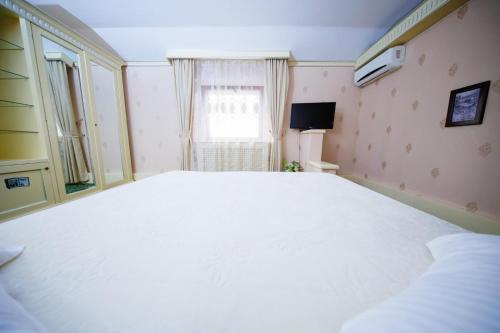 a large white bed in a room with a window at Cazare Plopii fara Sot in Iaşi