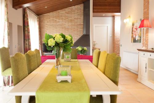 una mesa de comedor con sillas verdes y un jarrón de flores en Casa Tapioles, en Basella