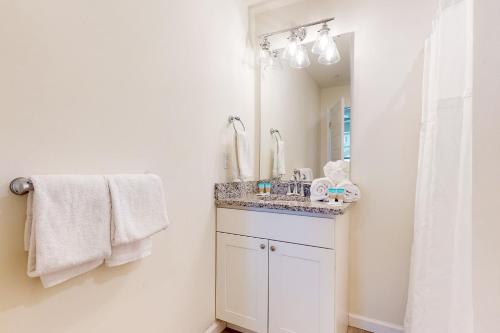 Baño blanco con lavabo y espejo en Rehoboth Beach House --- 20494 Coastal Highway Unit #9 en Rehoboth Beach