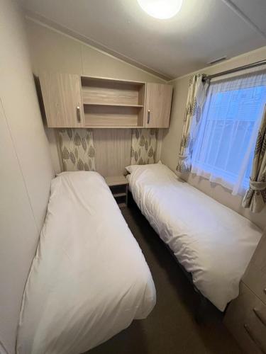 two beds in a small room with a window at Our Lodge at Newquay Bay NB35 in Newquay