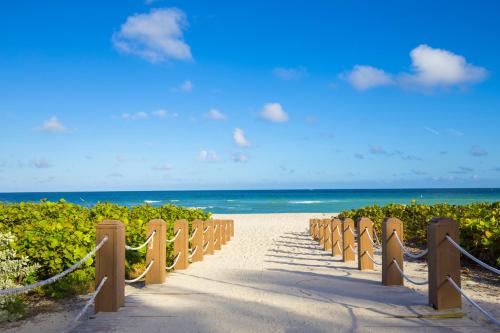 a pathway to the beach with the ocean in the background at Oceanview Private Condo at 1 Hotel & Homes -906 in Miami Beach