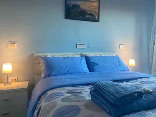 ein blaues Bett mit blauer Bettwäsche und Handtüchern darauf in der Unterkunft Civita Home in Bagnoregio