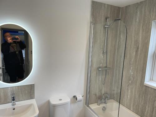 a man taking a picture of a shower in a bathroom at Dragonfly Cottage in Filey