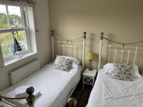 2 Einzelbetten in einem Schlafzimmer mit Fenster in der Unterkunft Dragonfly Cottage in Filey