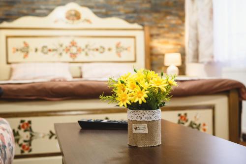a vase with yellow flowers on a table in a bedroom at Cozy Saxon Apartment - Sibiu Old Town - Walk to Main Square in Sibiu
