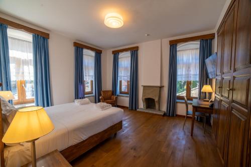a bedroom with a bed and a fireplace and windows at VILLA PERMET in Përmet