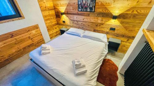 a bed in a room with a wooden wall at Appartamento Livia - Affitti Brevi Italia in Bardonecchia