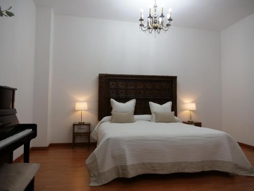 a bedroom with a large white bed with a chandelier at Villa María Montecastillo Golf in Jerez de la Frontera