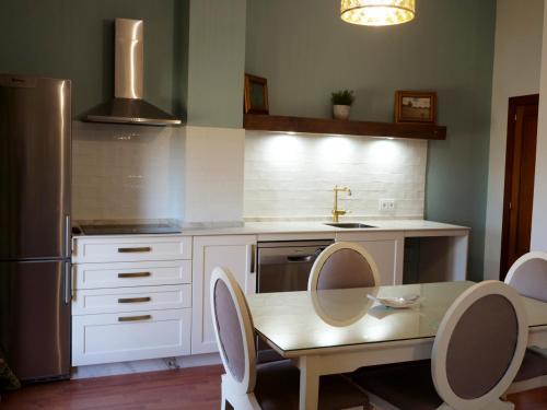 a kitchen with a table and a stainless steel refrigerator at Villa María Montecastillo Golf in Jerez de la Frontera