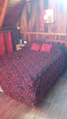 een slaapkamer met een bed met rode lakens en rode kussens bij Cabañas don luis 
