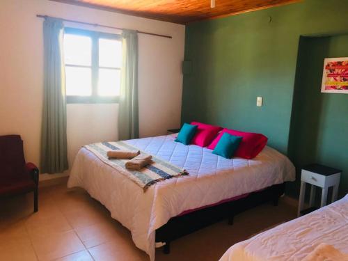 Un dormitorio con una cama con almohadas de colores y una ventana en Hospedaje Elias en Tilcara