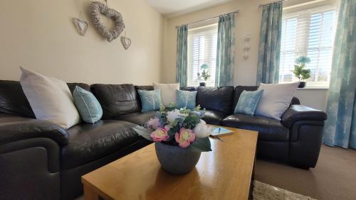 a living room with a couch and a table with a vase of flowers at Puddleduck Cottage - Part of the The Bay Filey Holiday Village with pool, gym and direct beach access, pub, restaurant, tennis and meadows walks in Filey