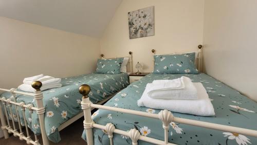 a bedroom with two twin beds with blue sheets at Puddleduck Cottage in Filey