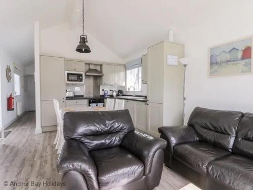 a living room with a leather couch and a kitchen at Sea-Renity - Part of the The Bay Filey Holiday Village with pool, gym and direct beach access, pub, restaurant, tennis and meadows walks in Filey