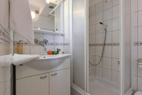 een witte badkamer met een wastafel en een douche bij Villa Katarina in Petrcane