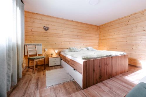 1 dormitorio con 1 cama y pared de madera en Apartmán Florián en Trenčianske Teplice