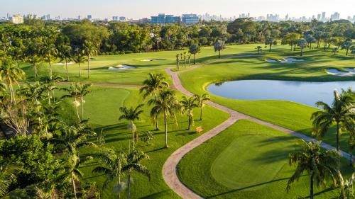 an aerial view of a golf course with palm trees and a pond at Oceanview Private Condo at 1 Hotel & Homes -1144 in Miami Beach