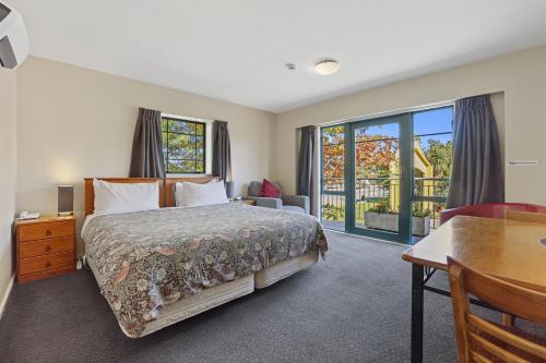 Schlafzimmer mit einem Bett, einem Schreibtisch und einem Fenster in der Unterkunft Denton Park Motel in Christchurch