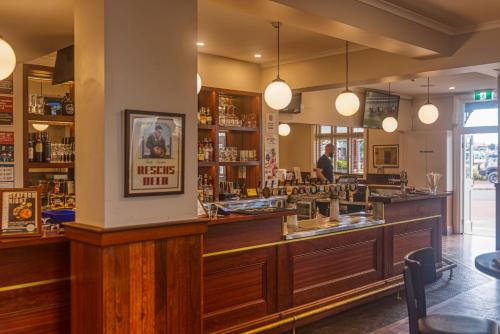 a bar in a restaurant with a man standing behind the counter at Royal Hotel Kew in Kew
