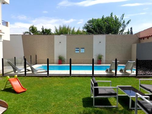 un patio trasero con piscina con sillas y toboganes en Apartamentos Ref en Salta