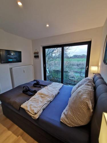 una camera da letto con un grande letto con una grande finestra di Tiny Home mit Panoramaterrasse - Ausblick ins Grüne inklusive a Wilhelmshaven