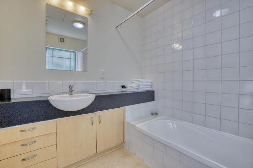 La salle de bains est pourvue d'un lavabo et d'une baignoire. dans l'établissement Denton Park Motel, à Christchurch