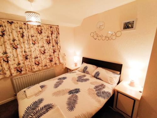 a bedroom with a bed and two tables with lamps at EEE Home Away From Home Dudley 