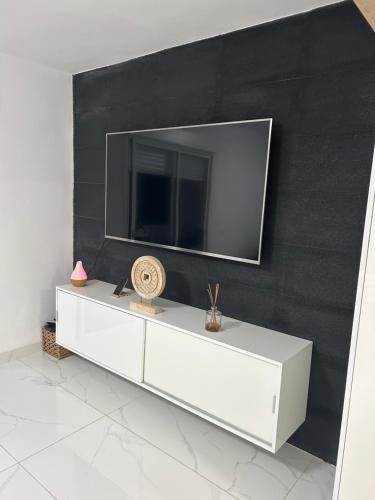 een witte dressoir met een televisie aan een zwarte muur bij ENZO SUITE in Las Palmas de Gran Canaria