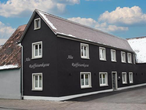 ein schwarzes Gebäude mit weißen Fenstern auf einer Straße in der Unterkunft Apartment Alte Raiffeisenkasse Rothenburg ob der Tauber in Rothenburg ob der Tauber