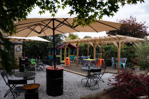 a patio with tables and chairs under an umbrella at Laburnum Guest House at Bistro En Glaze in Wylam