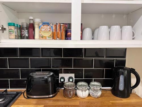 a kitchen counter with a tea pot and cups on a shelf at Victorian 3 BR main door flat, King size beds , large rooms in Glasgow