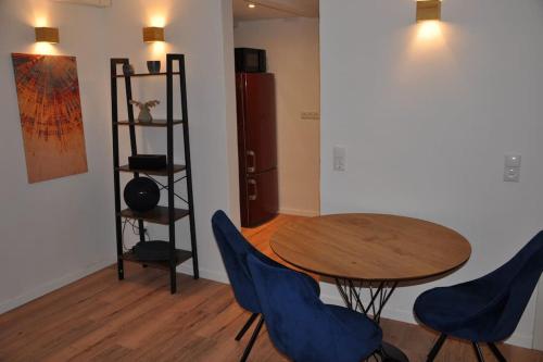 Cette chambre comprend une table en bois et des chaises bleues. dans l'établissement Stadtnaher heller Souterrain, à Oldenbourg