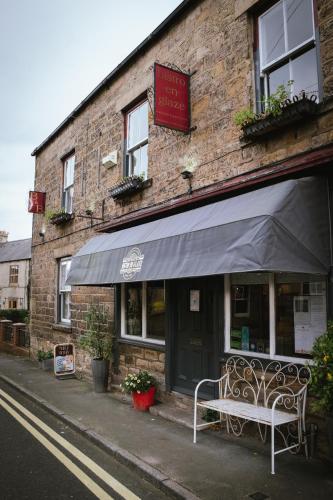 a bench sitting outside of a brick building at Laburnum Guest House at Bistro En Glaze in Wylam