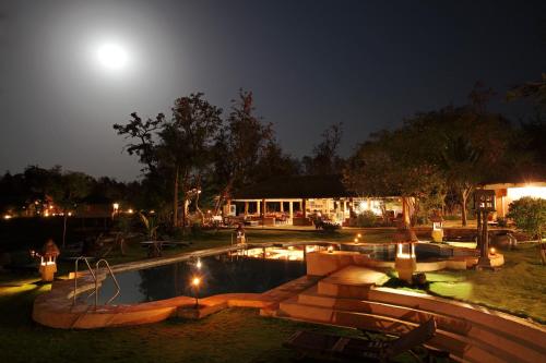 una piscina por la noche con la luna en el cielo en Tuli Tiger Resort, en Dhanwār