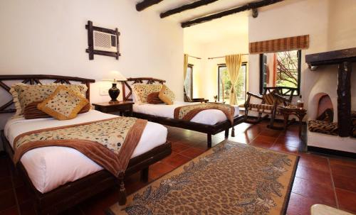 Tuli Tiger Resort في Dhanwār: غرفة نوم بسريرين ومدفأة