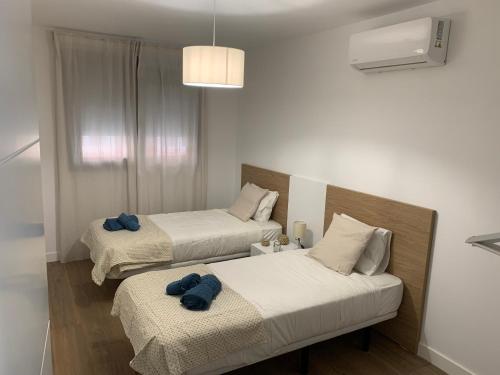 two beds in a room with blue towels on them at Apartamentos Central B in Algeciras