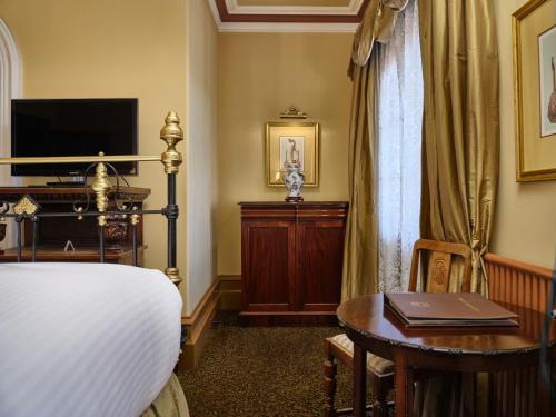 um quarto com uma cama, uma secretária e uma televisão em Craig's Royal Hotel em Ballarat