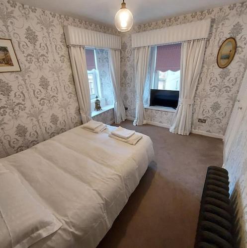 Lovely 1 Bed house in Largs, North Ayrshire في لارغس: غرفة نوم بسرير ابيض كبير ونافذة