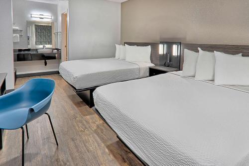 a hotel room with two beds and a blue chair at Motel 6-Lancaster, CA in Lancaster