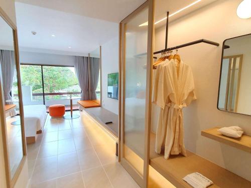 a dressing room with a mirror and a robe on a rack at Novotel Rayong Rim Pae Resort in Klaeng