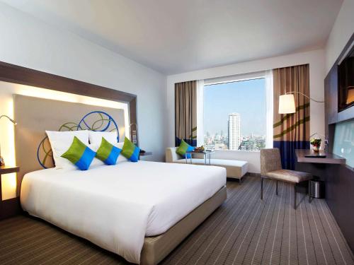 曼谷的住宿－Novotel Bangkok Ploenchit Sukhumvit，一间酒店客房,设有一张大床和一个大窗户