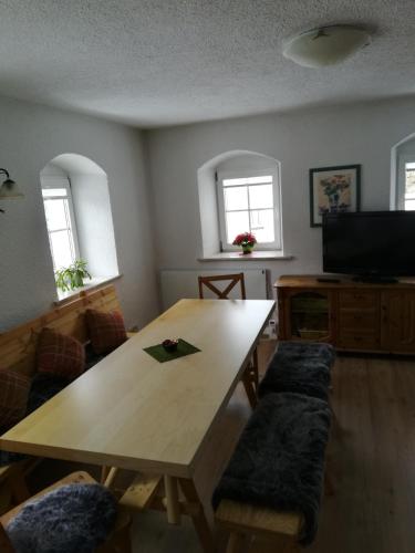 a living room with a wooden table and a television at Ferienhaus 3 Eulen in Kurort Altenberg