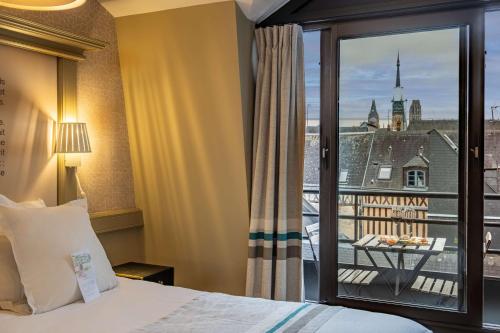 a hotel room with a bed and a balcony at Hôtel Littéraire Gustave Flaubert, BW Signature Collection in Rouen