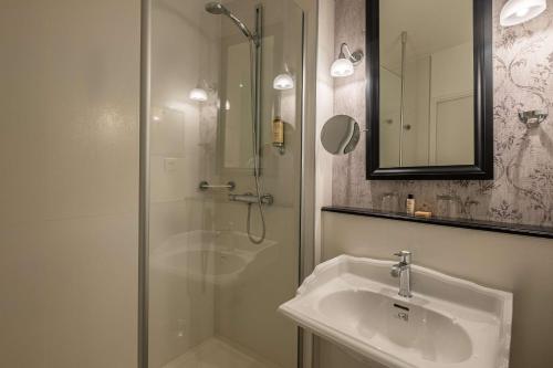 a bathroom with a shower and a sink and a mirror at Hôtel Littéraire Gustave Flaubert, BW Signature Collection in Rouen