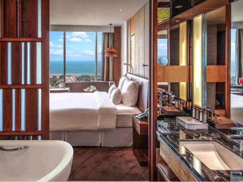 a bedroom with a bed and a bathroom with a sink at Pullman Vung Tau in Vung Tau